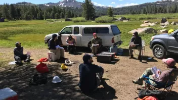 A group having outdoor field training near a forest with mountains in the background.
