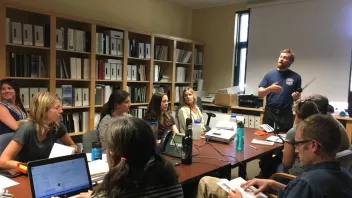 A man leading a training session in a conference room with participants seated around a table in a Radio Fire Safety training with the Field crews