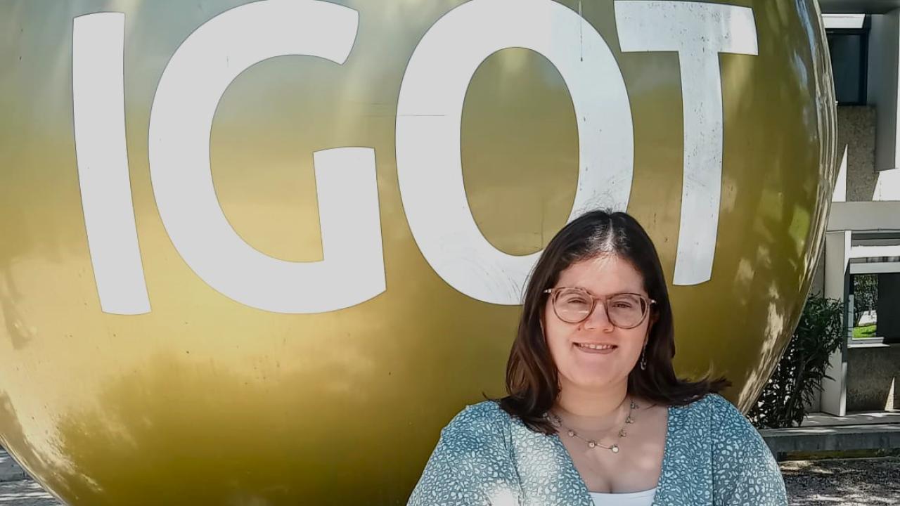 A person standing in front of a large, gold spherical sculpture with "IGOT" written on it.