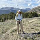 Full-length smiling girl on a hike with a mountain landscape in the background